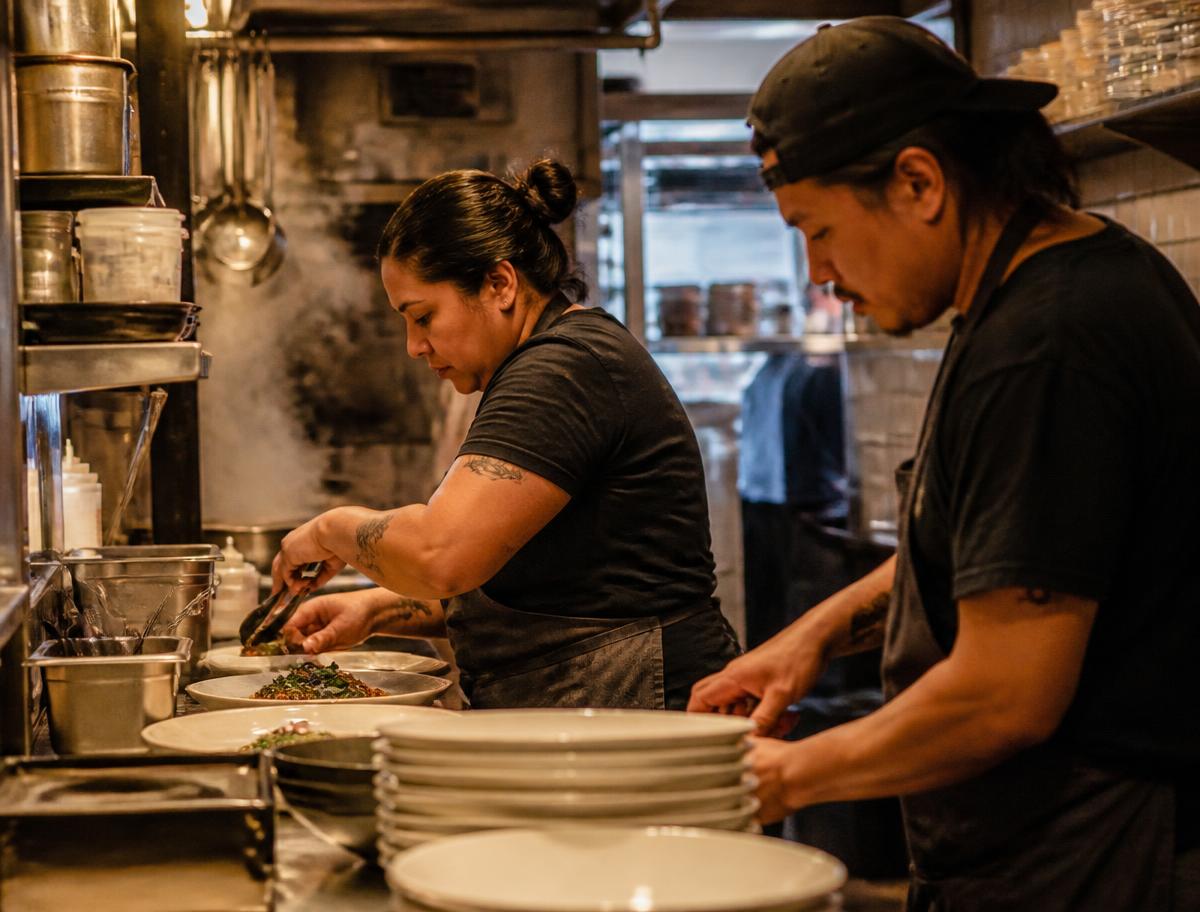 Two cooks plating dishes during a busy dinner service